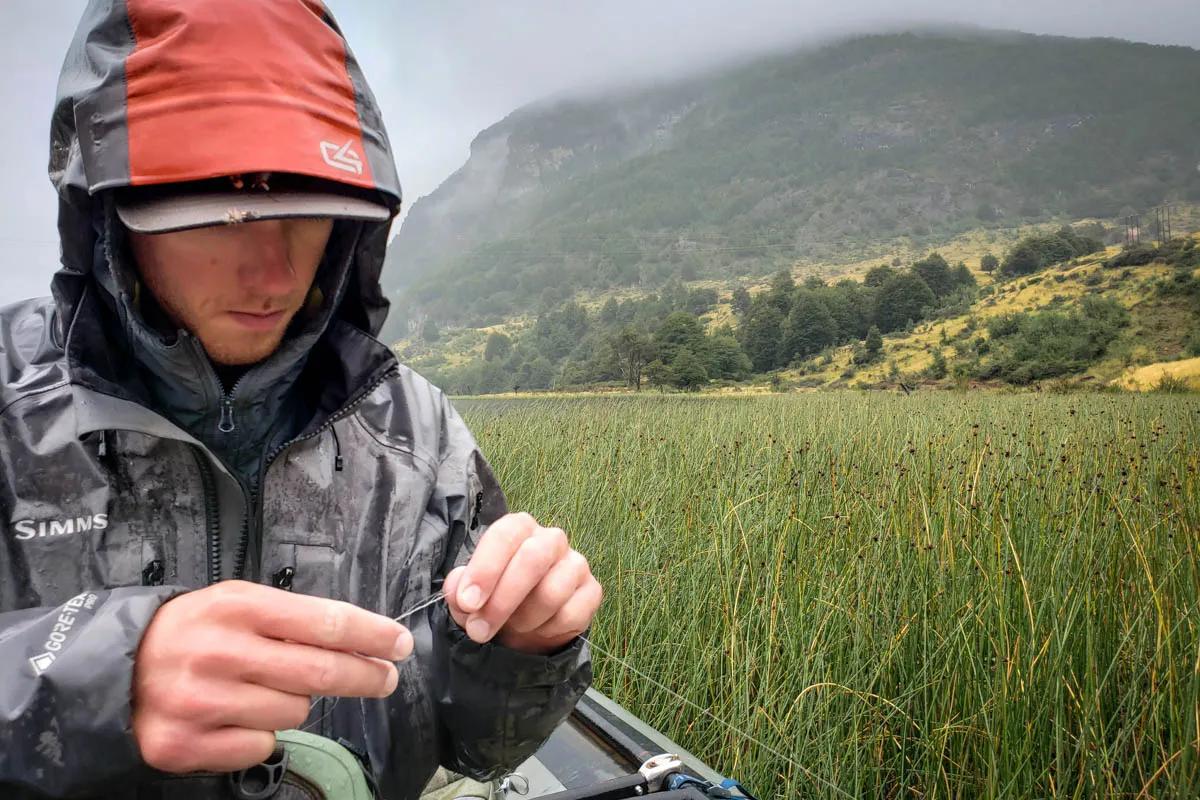 Lago Barroso Magic Waters guide Hayden ties on a dry fly during a rainy day on Lago Barroso
