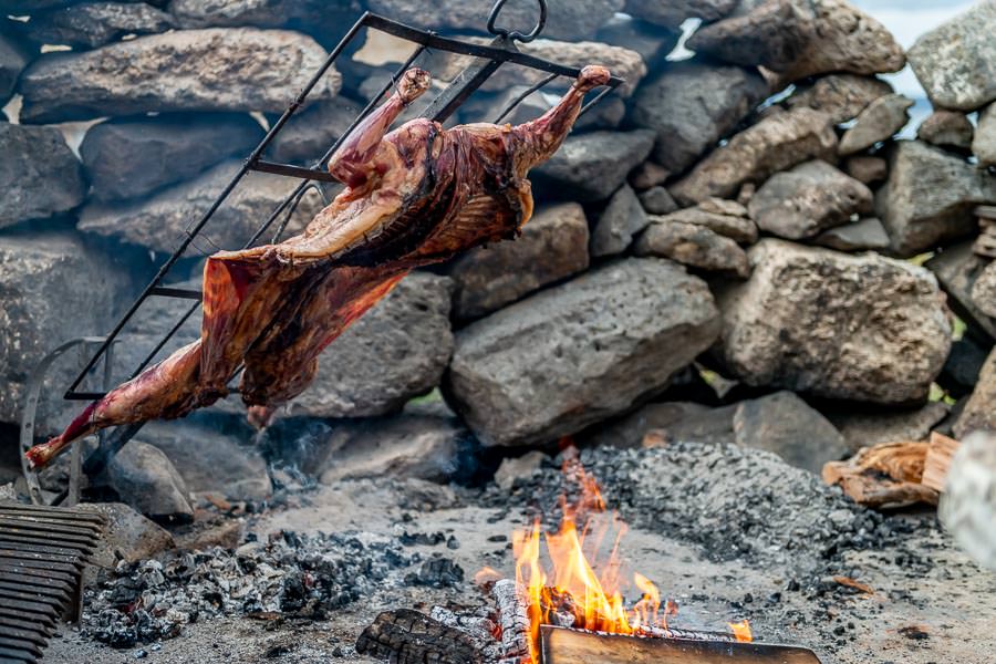 "... She was preparing for lamb asado. For this method of cooking a whole lamb is prepared and placed on a specially designed steel cross that allows you to adjust the angle of the lamb,  moving it closer or further away from the wood fire as needed. "