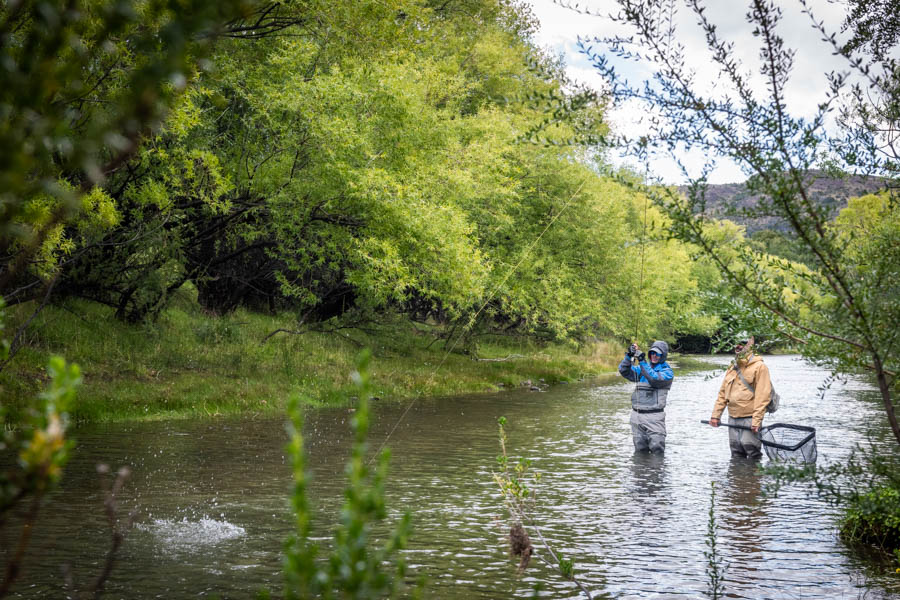 Corey, left, hooks into a brown trout while fishing with El Encuentro guide Marcello on the Rio Corinto